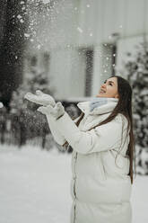 Frau hat Spaß beim Spielen mit Schnee im Winter - ANAF01041