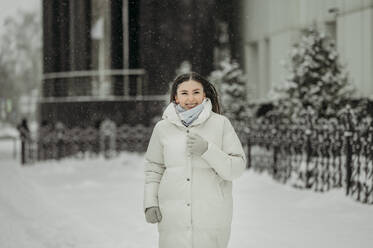 Glückliche Frau in warmer Kleidung beim Spaziergang im Winter - ANAF01042