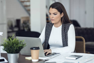 Businesswoman working on laptop at desk in office - JSRF02413