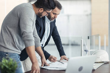 Architekten diskutieren über eine Blaupause auf dem Schreibtisch im Büro - JSRF02414