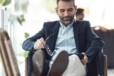 Smiling businessman using tablet PC at office - JSRF02429