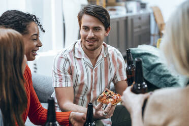 Smiling businessman having pizza with colleagues at office - JSRF02438