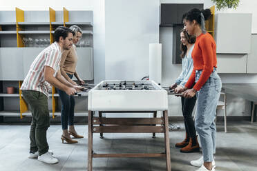 Business colleagues playing foosball together at office - JSRF02448