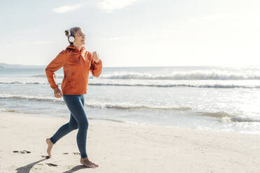 Frau joggt am Ufer des Strandes - AAZF00084
