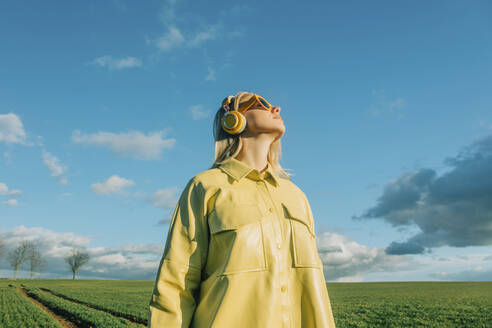 Frau mit gelbem Hemd steht unter blauem Himmel - VSNF00531