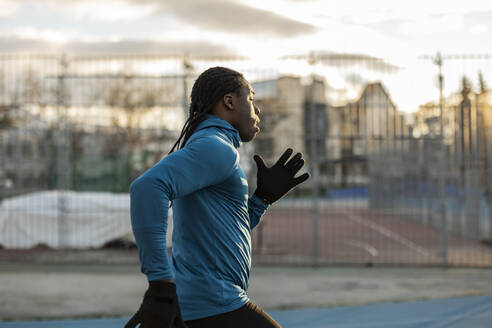 Young man running on sports track - JCCMF09483