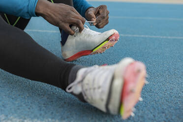 Athlete tying shoes on sports track - JCCMF09484