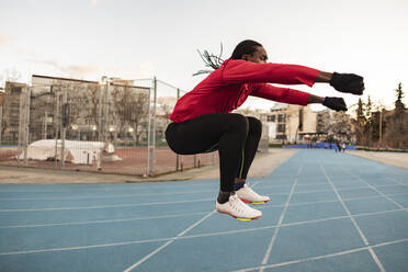 Athlete doing jumping exercise on sports track - JCCMF09489