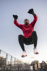 Mann macht hüpfende Kniebeugen auf einer Sportbahn - JCCMF09490