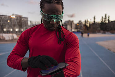 Athlete wearing smart glasses using tablet PC on sports track - JCCMF09493
