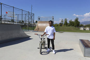 Young man standing with BMX bike at skatepark - SYEF00221