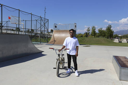 Junger Mann steht mit BMX-Rad im Skatepark - SYEF00221