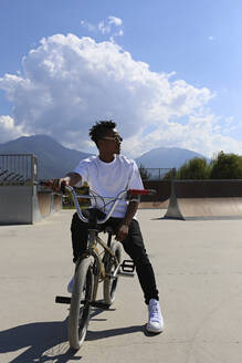 Junger Mann sitzt auf einem BMX-Rad im Skatepark - SYEF00222