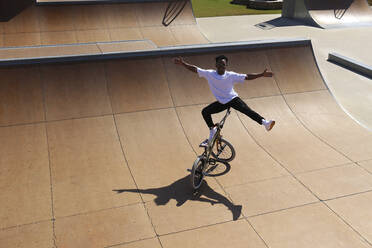 Young man balancing on BMX bike at skatepark - SYEF00226