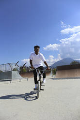 Young man riding BMX bike at skatepark - SYEF00231