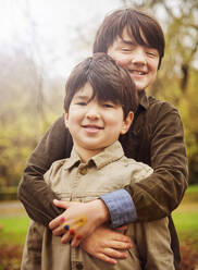 Glücklicher Junge umarmt seinen Bruder im Park - PWF00770