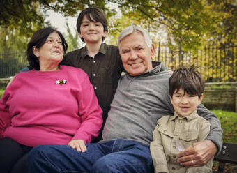 Lächelnde Enkel sitzen mit den Großeltern im Park - PWF00773
