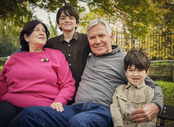 Smiling grandsons sitting with grandparents at park - PWF00773