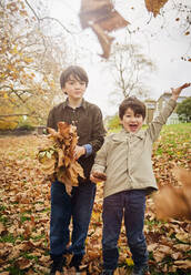 Fröhliche Jungen, die im Park Herbstblätter wegwerfen - PWF00792