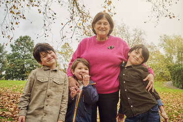 Lächelnde ältere Frau steht mit Enkeln im Park - PWF00796