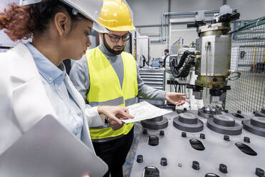 Ingenieur und Kollege bei der Überprüfung eines Bauplans in der Fabrik - AAZF00106