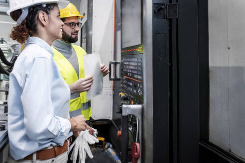 Lächelnde Ingenieure vor dem Bildschirm der Steuertafel in der Fabrik - AAZF00123