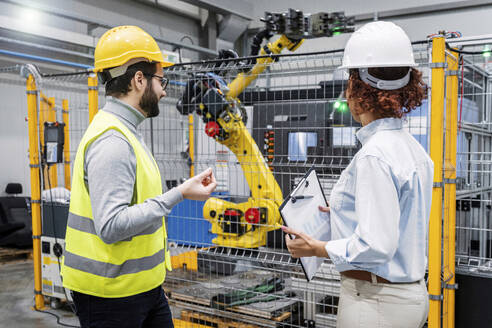 Ingenieure untersuchen einen Roboterarm in einer Fabrik - AAZF00127