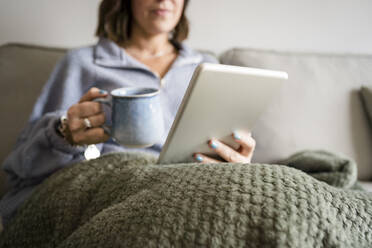 Frau benutzt Tablet-PC auf dem Sofa zu Hause - JJF00291