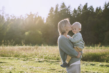 Mother kissing son on sunny day - NDEF00376