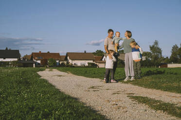 Familie genießt gemeinsam auf dem Fußweg stehend - NDEF00378