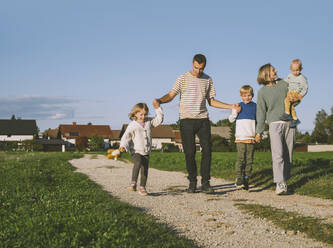 Vater hält die Hände von Sohn und Tochter, die auf dem Fußweg gehen - NDEF00380