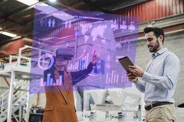 Geschäftsfrau mit VR-Brille und Kollege mit Tablet-PC in einer Fabrik - EBBF08105