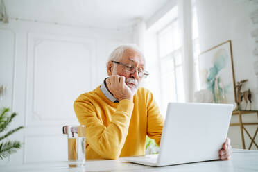 Älterer Freiberufler arbeitet am Laptop am Schreibtisch - MDOF00657