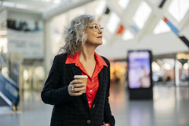 Reife Geschäftsfrau mit Einweg-Kaffeebecher an der U-Bahn-Station stehend - JCCMF09524