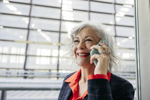 Happy mature businesswoman talking through smart phone - JCCMF09543