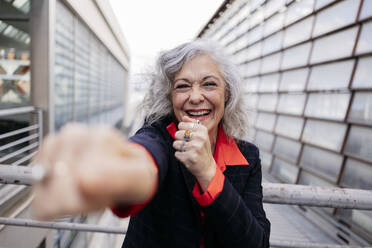 Happy mature businesswoman punching in front of railing - JCCMF09554