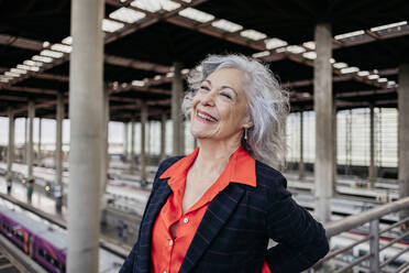 Cheerful mature businesswoman with gray hair at station - JCCMF09558