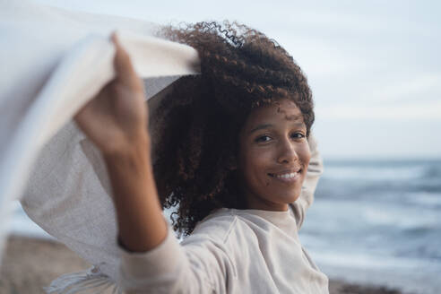 Happy woman with scarf in front of sea at beach - JOSEF17264