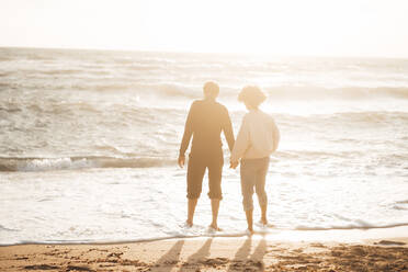 Mann hält Hände mit Frau am Strand stehend - JOSEF17270