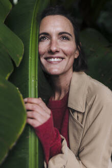 Glückliche Frau umarmt grünes Bananenblatt - JOSEF17300