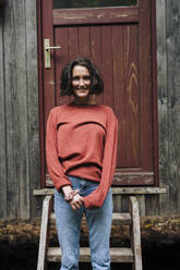 Smiling woman standing in front of door - JOSEF17320