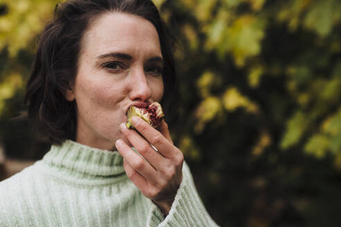 Woman eating fig in back yard - JOSEF17337