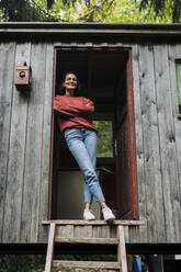 Smiling woman with arms crossed standing in doorway - JOSEF17377