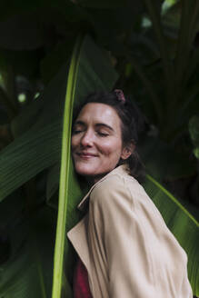Lächelnde Frau, die ein Bananenblatt umarmt - JOSEF17395