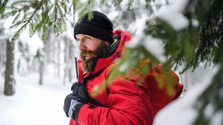 Rettungssanitäter vom Bergrettungsdienst mit Walkie-Talkie im Freien im Winter im Wald. - HPIF06077