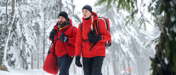 Rettungssanitäter des Bergrettungsdienstes gehen im Winter im Wald spazieren und unterhalten sich. - HPIF06078