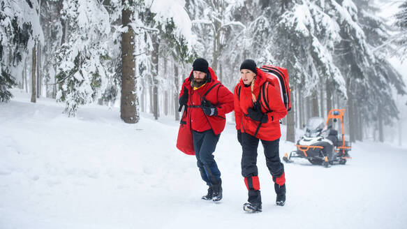 Rettungssanitäter des Bergrettungsdienstes gehen im Winter im Wald spazieren und unterhalten sich. - HPIF06082