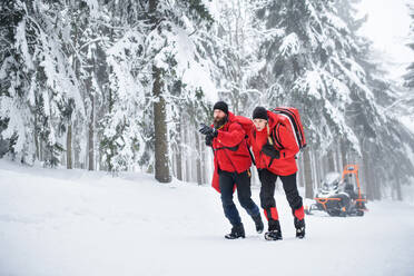 Rettungssanitäter des Bergrettungsdienstes gehen im Winter im Wald spazieren und unterhalten sich. - HPIF06083