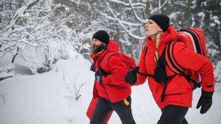 Sanitäter eines Bergrettungsdienstes laufen im Winter draußen im Wald. - HPIF06086