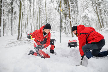 Mountain rescue service on operation outdoors in winter in forest, digging snow with shovels. Avalanche concept. - HPIF06096